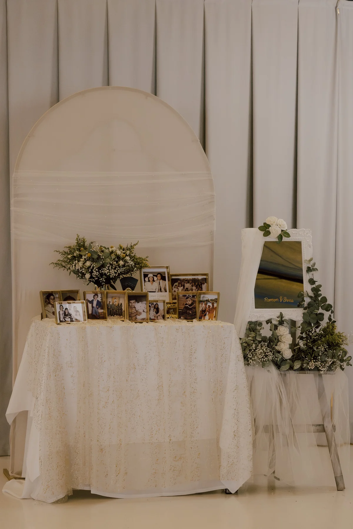 Racó de fotografies familiars, flors i mirall amb fons de tela blanca