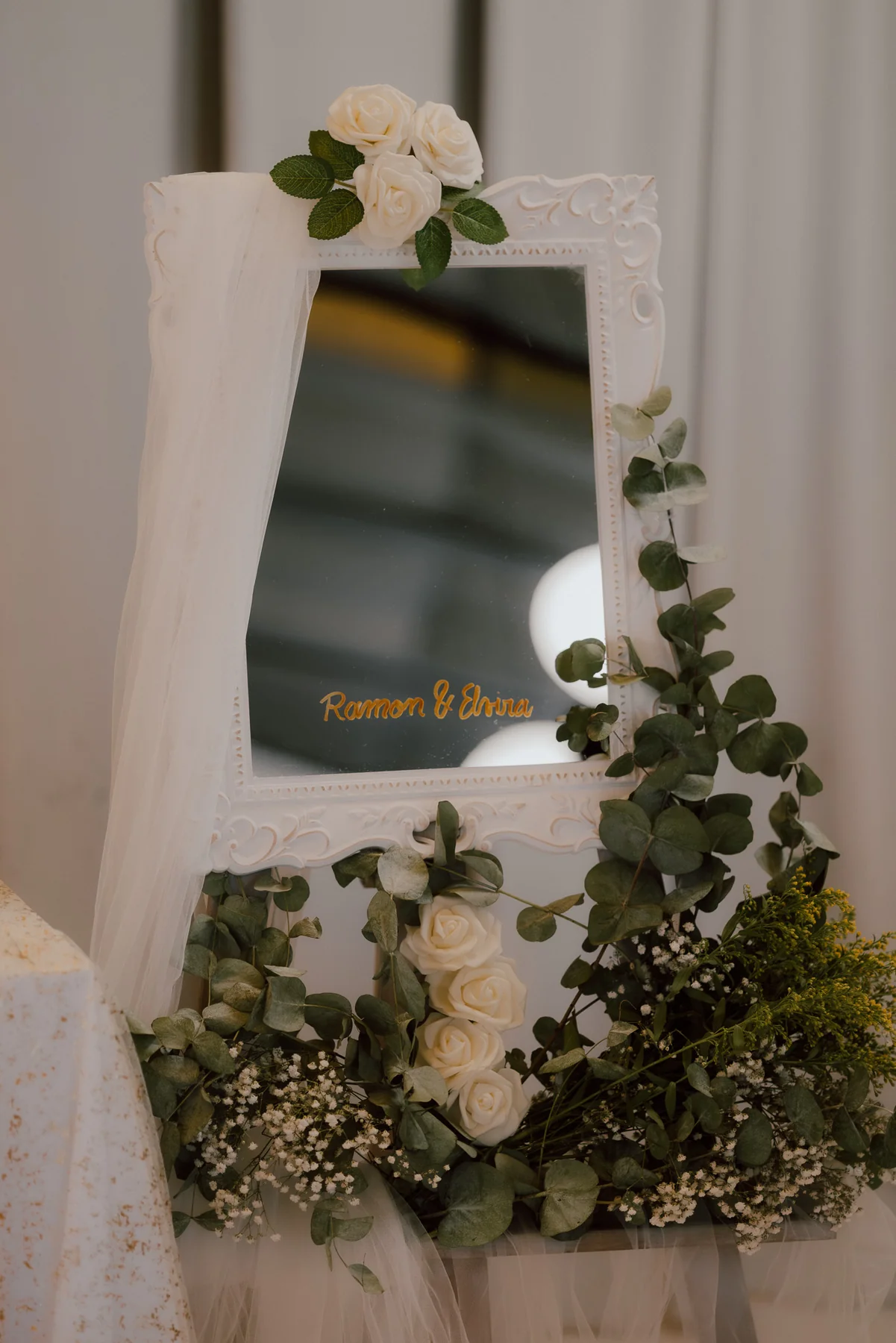 Mirall decorat amb tul blanc, flors i fullatge